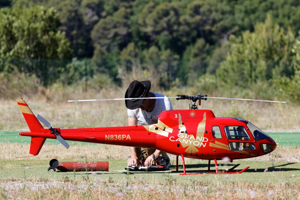 l’immagine rappresenta un elicottero radiocomandato elettrico ed un uomo che lo sta settando per farlo alzare in volo